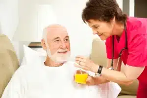 nurse feeding orange juice to patient