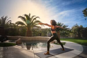 female doing yoga in backyard next to pool